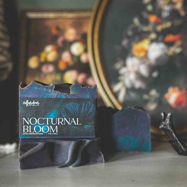 Bar of soap named 'Nocturnal Bloom' in front of a decorative still life painting.